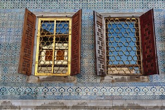 Two barred windows with shutters in mosaic wall