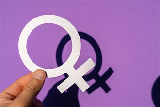 A woman holding the female symbol on a purple background