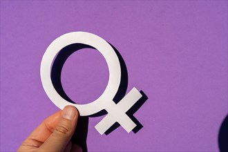 A woman holding the female symbol on a purple background