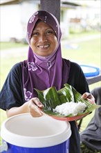 Malaysian woman with headscarf showing rice in banana leaf