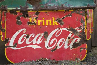 Vintage Drink Coca Cola advertising sign in front of wood plank storage shed