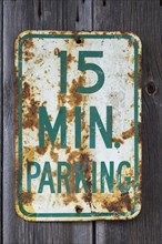 Old 15 minute parking sign displayed on side wall of wood plank storage shed