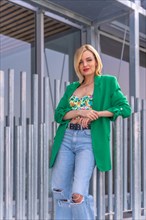 Portrait of a blonde model woman in a green jacket in a beautiful building in the city