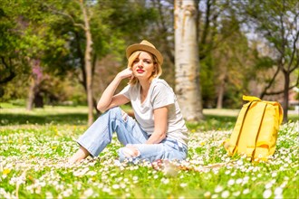 A young blonde girl in a hat enjoying spring in a park in the city