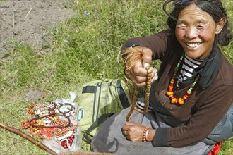 Tibetan woman holding jewellery to the camera