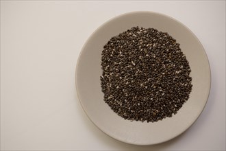 Close-up of chia seeds on a white plate isolated on a white background