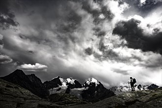 Climbers in front of summit of Bernina Group with dramatic clouds