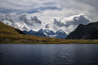 Mountain lake Lej Suvretta with Bernina group and Engadine mountains with cloudy sky