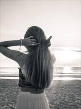 Young woman in shirt looking at the sea and keeps her hair