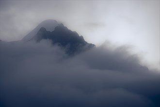 Peak of Piz Rosegg in dramatic clouds at blue hour