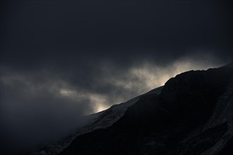Peak of Piz Rosegg in dramatic clouds at blue hour