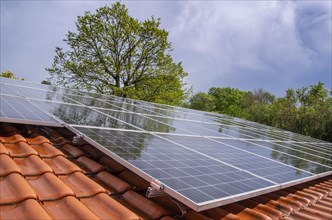 Wet photovoltaic system on a tiled roof after a spring thunderstorm