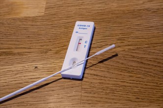Close-up of a negative Corona rapid test cassette with collection sticks on a wooden table