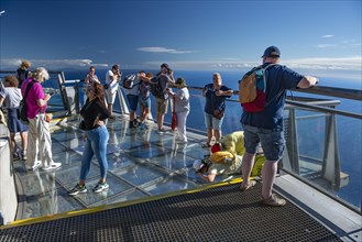 Tourists look at the view from the glass-bottom skywalk