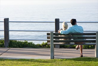 Young couple sitting on a bench by the seaside