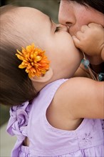 A baby girl kissing her mother