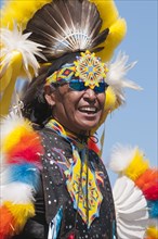Adult First Nations man at a pow wow wearing colorful regalia