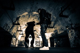 Two men as silhouette in bunker with graffiti walls