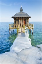 Iced wooden bathhouse in sunshine and blue sky on Lake Neuchatel in Gorgier