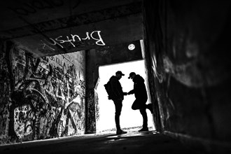 Two men as silhouette in bunker with graffiti walls