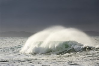 Big wave breaks in winter storm in open sea and dramatic light off north coast of Ireland