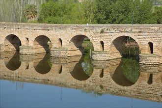 Historic UNESCO bridge Puente Romano as part of the Roman city Emerita Augusta with reflection in the Rio Guadiana in Merida