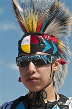 Young Blackfoot boy in traditional regalia and sunglasses