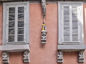 Detail of a house in the old town with figures under and between the windows
