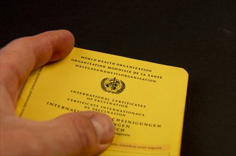Hand holding a German vaccination certificate against a black background