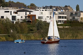 A sailboat and a pedal boat in front of the houses at the Phoenix See in Dortmund