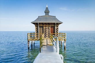 Iced wooden bathhouse in sunshine and blue sky on Lake Neuchatel in Gorgier