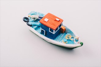 Little colorful model fishing boat placed on white