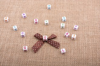 A ribbon and scattered dice-sized alphabet cubes on a textured surface in display