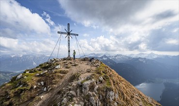 Hiker at the summit of Rote Flueh with summit cross