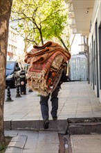 Man carrying Turkish carpet and rugs on his back