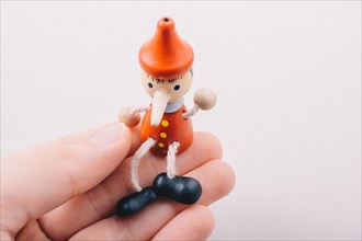 Wooden pinocchio doll in hand on a white background