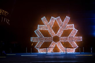 Large white snowflake model on a wall outdoors