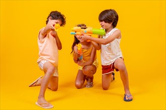 Kids having fun with water pistols on summer vacations and aiming at camera