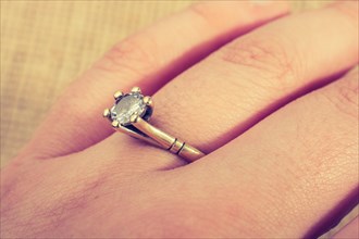 Hand wearing a fake diamond ring on a textured background