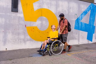 Disabled person in a wheelchair with a cement wall
