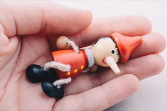 Wooden pinocchio doll in hand on a white background