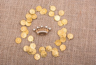 Crown in the middle of golden coins in a textured background