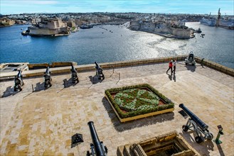 View over former parade ground with saluting cannons Battery Saluting Batter and flower bed in the form of Maltese Cross from historic Order of St. John next to Upper Barraka Garden on left Fort St. A...