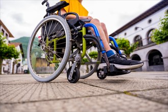 Detail of a disabled person in a wheelchair walking through the town square