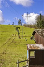 Ski lift at standstill due to lack of snow caused by climate change at the end of winter on a hill in Muensingen