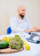 Focus on vegetables of nutritionist with laptop at the desk. Nutritionist working on laptop