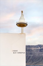 White street lamp on the corner of white house with volcanic Lanzarote island background