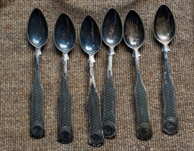 Stylish steel teaspoons on a textured background in display