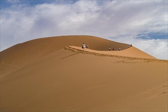 Tourists climb the Sossusvlei dunes