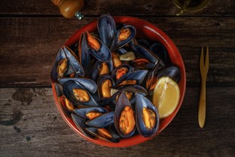 Steamed mussels with lemon in clay pot with metal mortar and pepper shaker